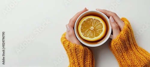 Warm cup of tea with lemon slices in cozy hands wearing knitted sweater