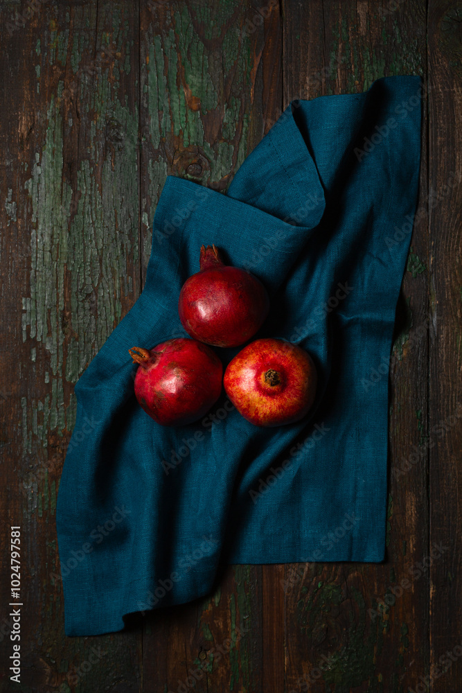 Ripe pomegranates on a turquoise linen napkin on a wooden table
