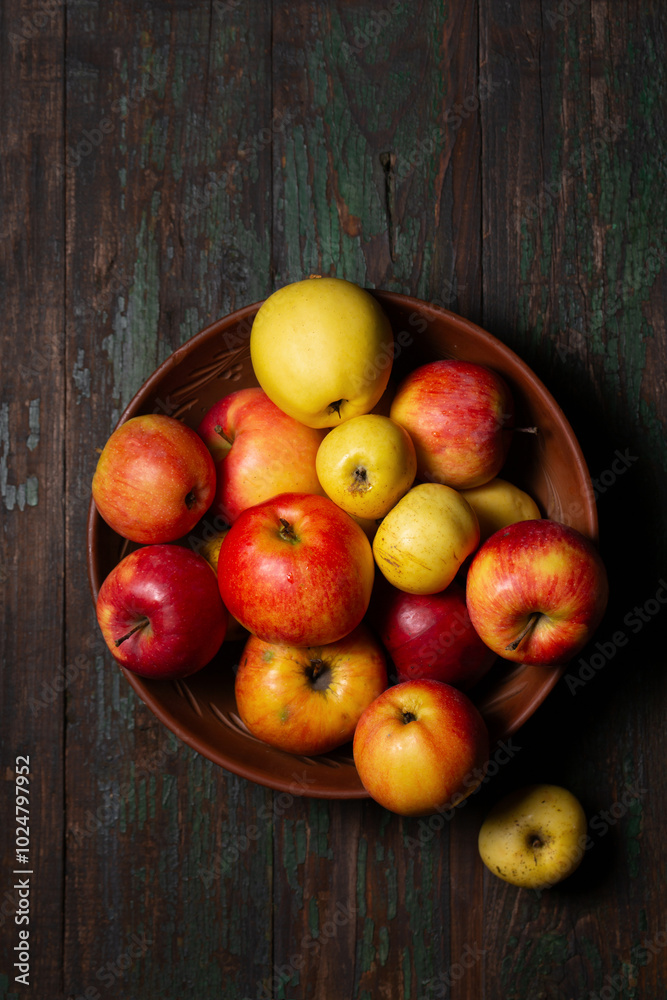 Juicy ripe apples in a large clay bowl on a wooden background Juicy ripe apples in a large clay bowl on a wooden background