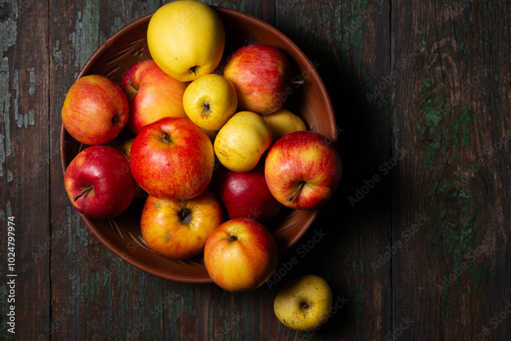 Juicy ripe apples in a large clay bowl on a wooden background Juicy ripe apples in a large clay bowl on a wooden background