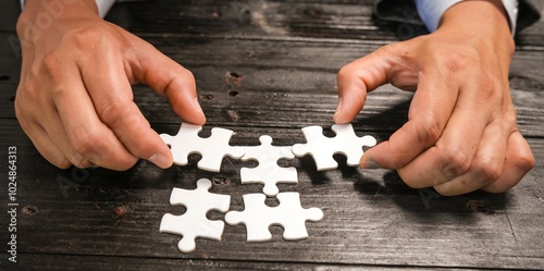 A group of people are putting together a jigsaw puzzle and trying to put the pieces together. This is a scene where everyone is working together on a wooden table, holding a jigsaw puzzle.