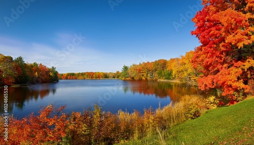 scenic autumn landscape featuring a serene lake surrounded by vibrant fall foliage in the picturesque countryside of minnesota or wisconsin on a sunny day