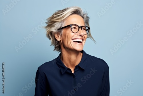 Portrait of a happy mature businesswoman laughing against blue background.