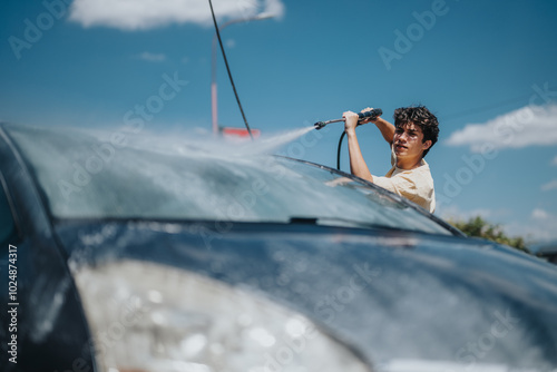 Foto A young man uses a high-pressure hose to wash his car on a sunny day