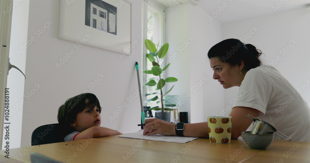 Mother struggling to homeschool her son at a desk, focusing on educational activities in a bright and airy living space Mother struggling to homeschool her son at a desk, focusing on educational activities in a bright and airy living space