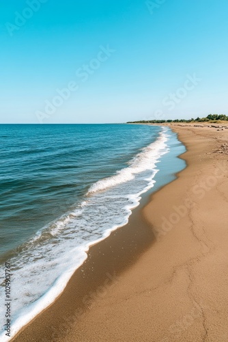 A serene beach scene with gentle waves lapping against a sandy shore under a clear sky.