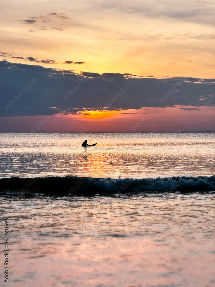 Fototapeta premium A surfer waits for waves at sunset, Andaman Sea/KohPayam, Thailand, Southeast Asia