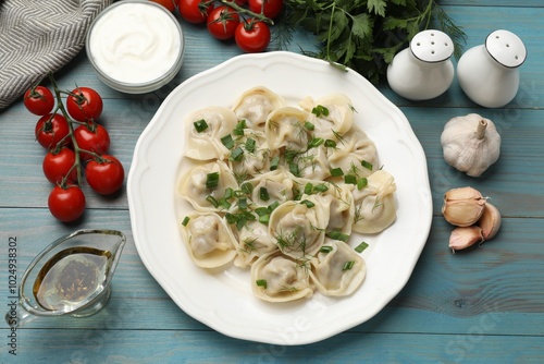 Delicious pelmeni with green onion served on blue wooden table, flat lay