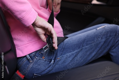 Pregnant woman fastening safety belt in car, closeup