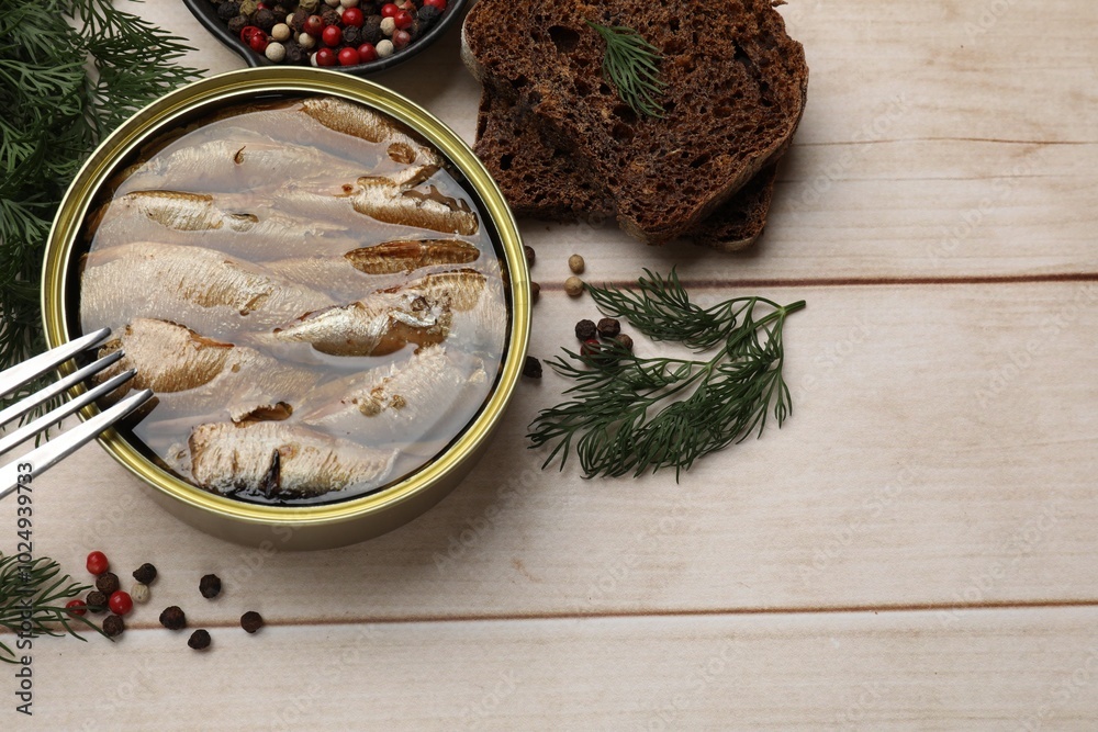 Tasty sprats in tin can, dill, bread and peppercorns on wooden table, top view Tasty sprats in tin can, dill, bread and peppercorns on wooden table, top view