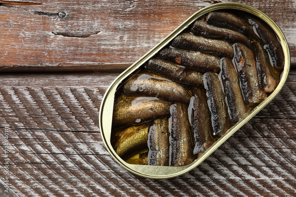 Tasty sprats in tin can on wooden table, top view Tasty sprats in tin can on wooden table, top view