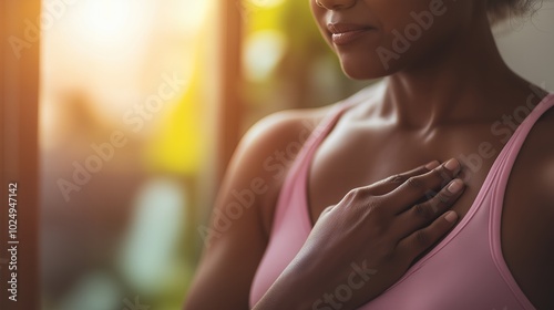 Close up of a woman's hand resting on her chest, wearing a pink sports bra.