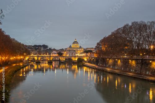 View over the Tiber River in a historic city. The old well-known bridge Ponte Sant'Angelo, in the evening. Rainy weather at sunset and view of the Basilica di San Pietro, Rome, Italy