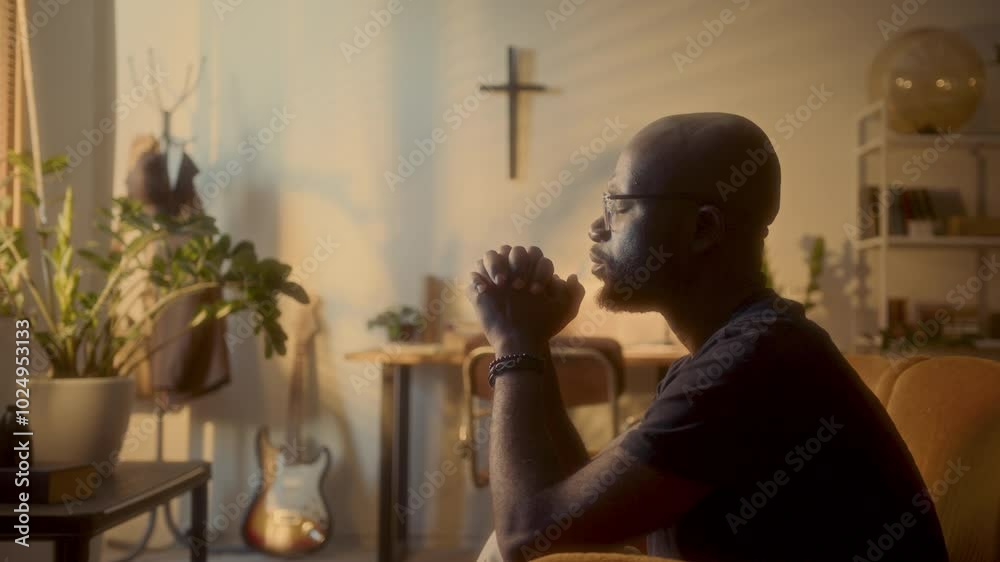 Black man praying to God, sitting in softly lit domestic room with his ...