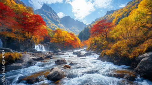 A wide river flowing through a valley surrounded by tall, rugged mountains. The trees on the mountainside are in full autumn colors, with shades of red, orange, and yellow. 