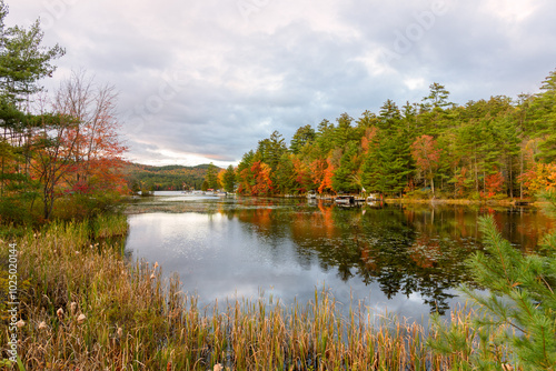 Motorboats moored to jetties along the forested shores of a mountain lake during the autumn colours season