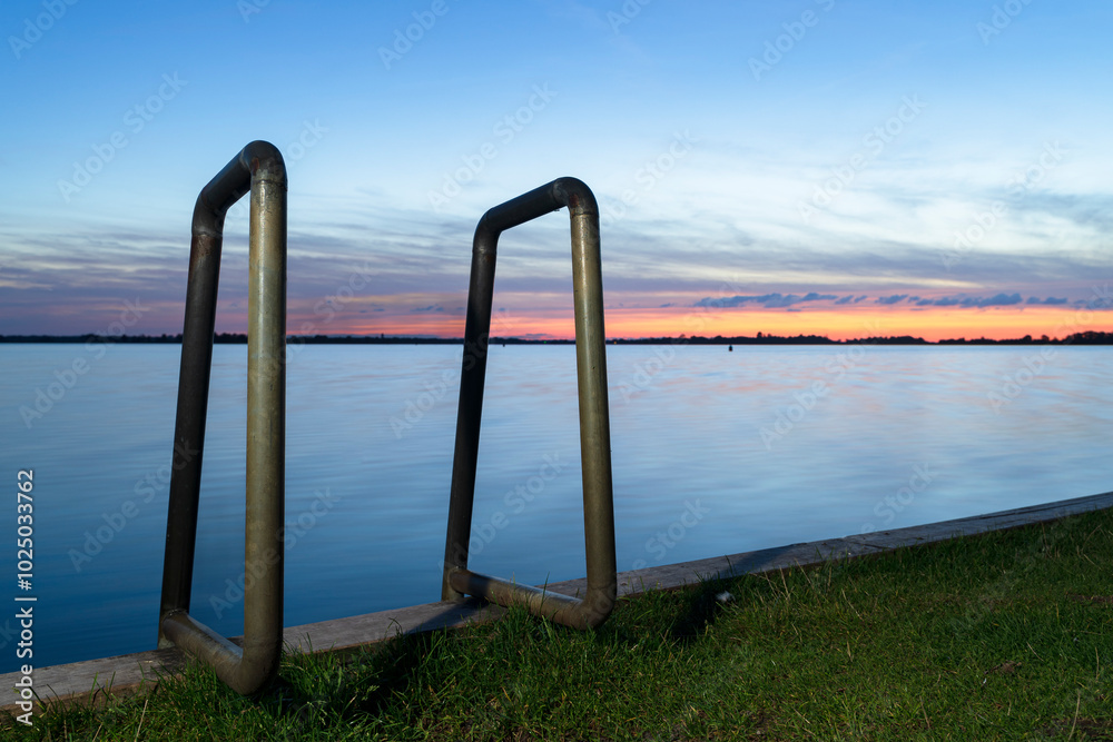 Sunset view of swimming ladder at the lakeside at dawn