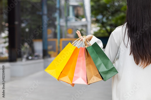 Businesswoman holding shopping paper bags in a shopping mall and is happy after shopping for her needs during the festival. Paper bags containing a lot of products are in hands of Asian businesswoman.
