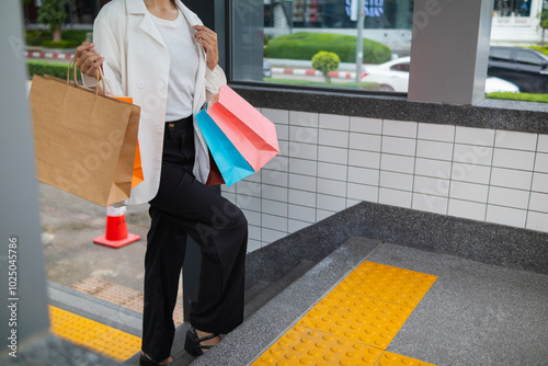 Businesswoman holding shopping paper bags in a shopping mall and is happy after shopping for her needs during the festival. Paper bags containing a lot of products are in hands of Asian businesswoman.