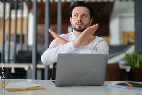 Obraz na plátně A man is sitting at a desk with a laptop in front of him