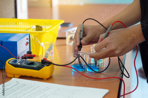 Students use a digital multimeter to measure electrical potential differences in a chemistry experiment on galvanic cells. soft and selective focus.