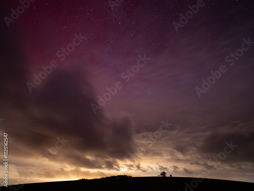 Red glowing sky due to aurora borealis on the 11. October 2024 in Germany. Dramatic sky and reflecting light of the city beneath. Light pollution caused by a city in Saxony. Northern lights in Europe. photo