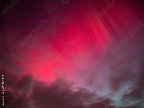 Red polar lights high up in the sky. Rays of the aurora borealis above the cloud layers. Bright glowing northern lights on the 11. October 2024 after a coronal mass ejection (CME) of the sun. photo