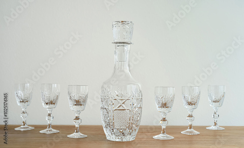 Elegant empty bottle and small crystal glasses with high stem on the brown wooden table. Close-up. Copy space. Selective focus.