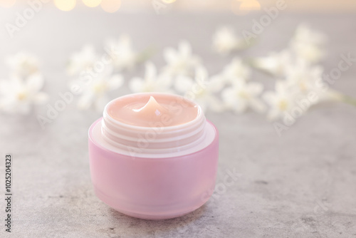 Cream in jar on grey table, closeup. Cosmetic product