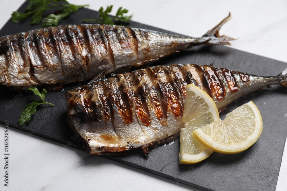 Delicious grilled mackerel and lemon on white table, closeup Delicious grilled mackerel and lemon on white table, closeup