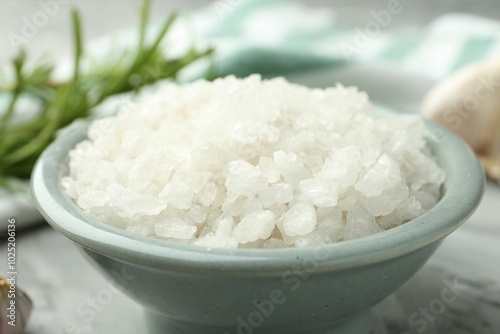 Sea salt in bowl on gray table, closeup