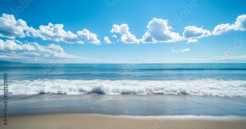 Gentle waves crashing on a sandy beach under a blue sky