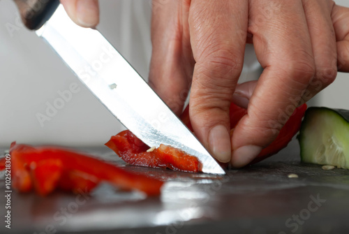 Close-up of a woman's hands cutting vegetables with a knife on a cutting board. Home cooking concept, gastronomy, veganism.