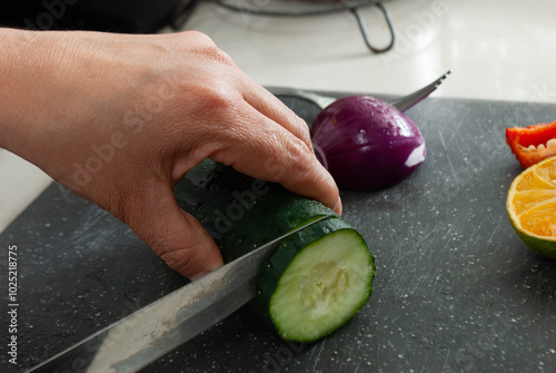 Close-up of a woman's hands cutting vegetables with a knife on a cutting board. Home cooking concept, gastronomy, veganism.