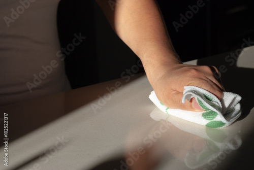 A woman's hand wiping the surface of the table in the kitchen with a rag and detergent spray. Cleaning concept