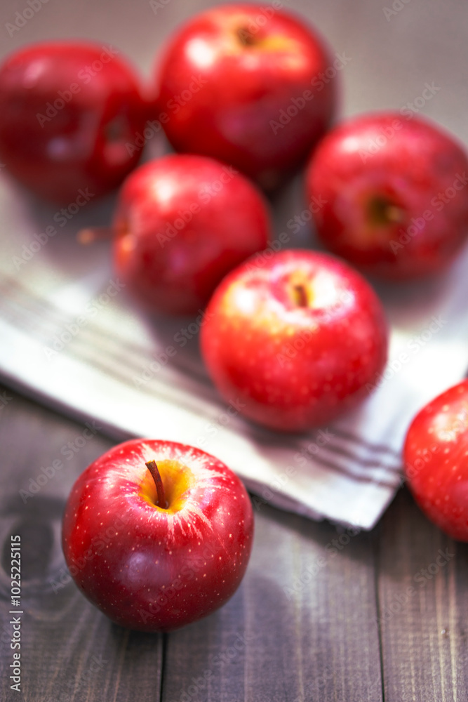 Bright red apples on a wooden surface with a blurred background and one apple in the foreground. Bright red apples on a wooden surface with a blurred background and one apple in the foreground.