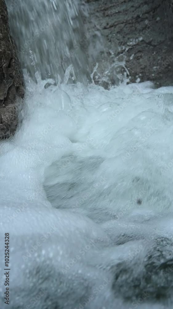 Water flushing into a pool between rocks in the mountains, slow motion, vertical shot Water flushing into a pool between rocks in the mountains, slow motion, vertical shot