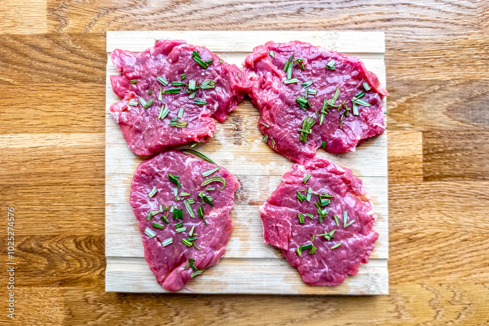 Sliced raw rib eye steak with rosemary and olive oil