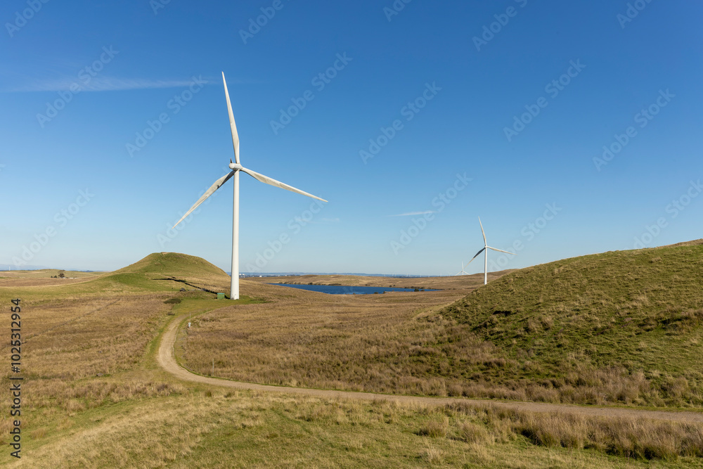 Renewable green energy wind farm with many turbines near freshwater reservoir lake on wild grassy moor in Scottish countryside Renewable green energy wind farm with many turbines near freshwater reservoir lake on wild grassy moor in Scottish countryside