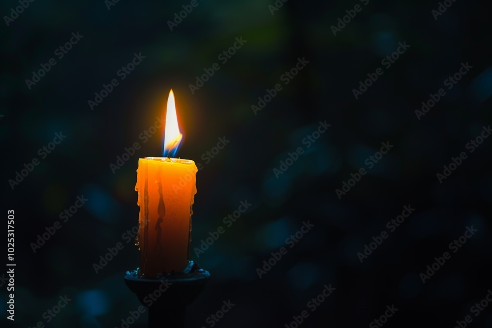 A single candle burning brightly in the darkness, casting its warm light on... A single candle burning brightly in the darkness, casting its warm light on...
