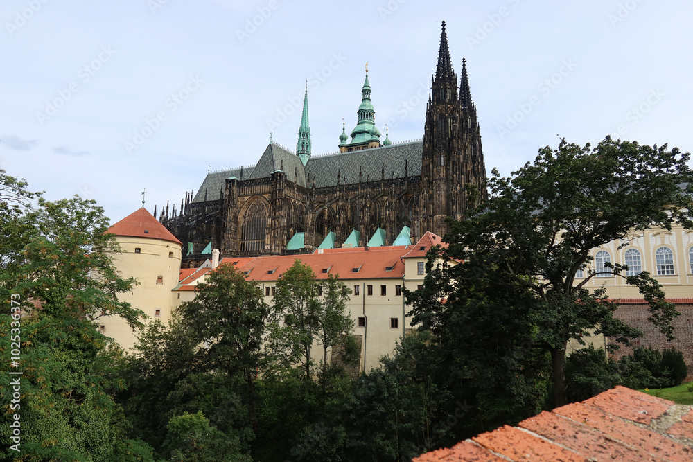Scenic View of St. Vitus Cathedral's Gothic Towers and Historic Prague Castle Buildings Amid Lush Greenery Scenic View of St. Vitus Cathedral's Gothic Towers and Historic Prague Castle Buildings Amid Lush Greenery