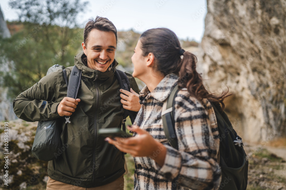 Fototapeta premium couple take a break from hiking and use mobile phone having fun