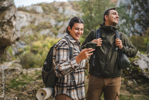 couple take a break from hiking and use mobile phone having fun