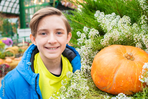 Portrait of smiling 12 year old boy with pumpkin at autumn festival photo