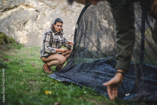 Adult woman set up a tent in a serene mountainous landscape scene photo