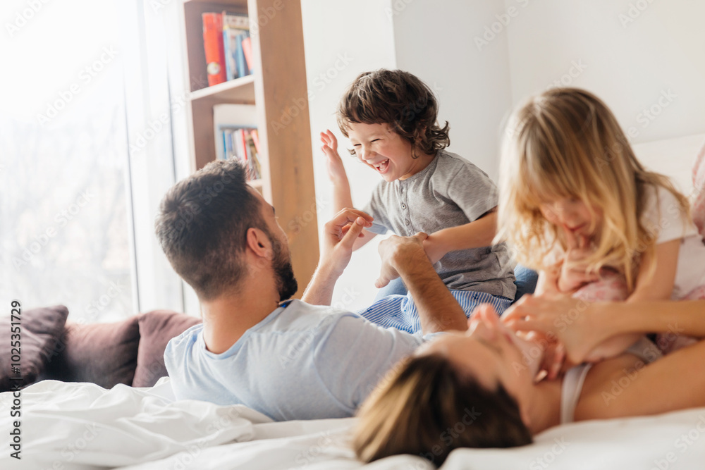 Family playing and laughing together in bed during the morning Family playing and laughing together in bed during the morning