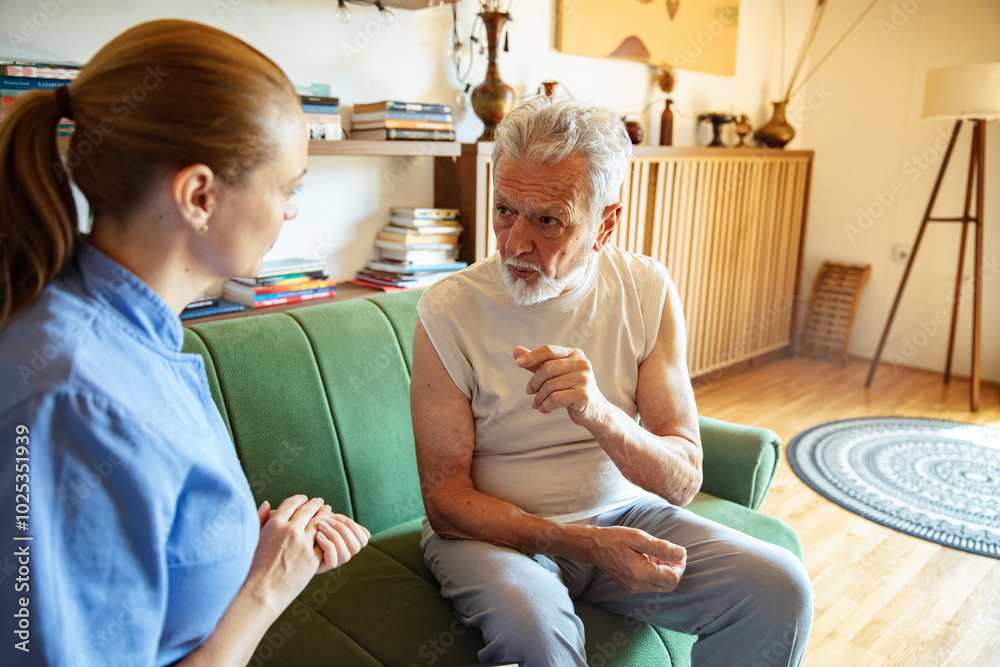 Obraz premium Female caregiver helping senior man at home