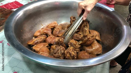 Asian adult woman choosing soy sauce pork side dish at a stall in a traditional market
