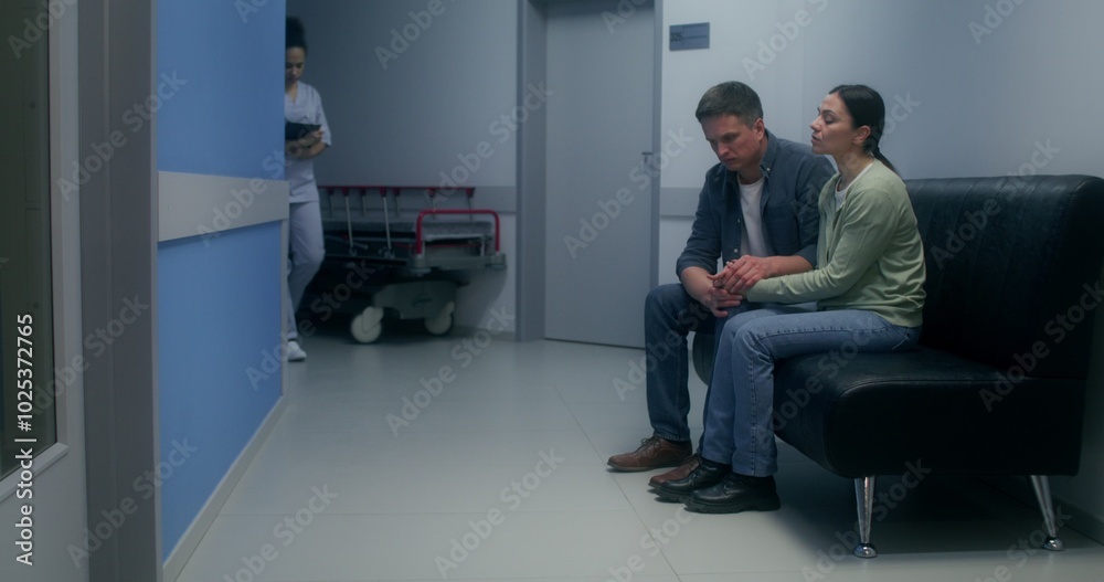 Relatives are waiting for the operation result, sitting in the hospital corridor and holding hands, they are scared and excited Relatives are waiting for the operation result, sitting in the hospital corridor and holding hands, they are scared and excited