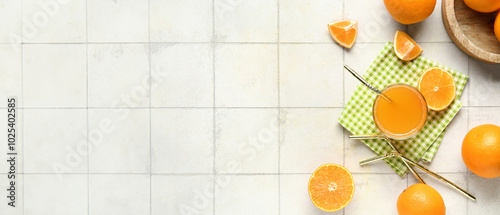 Glass of tasty juice with fresh oranges and straws on white tile background